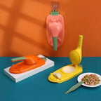 Colorful kitchen tools shaped like a carrot, boat, and banana on a blue surface with an orange wall background.