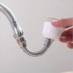 Hand holding a white kitchen sprayer with a flexible hose attached to a faucet on a light gray background