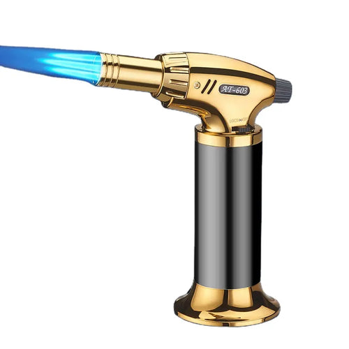 Gold and black butane torch with blue flame on a white background