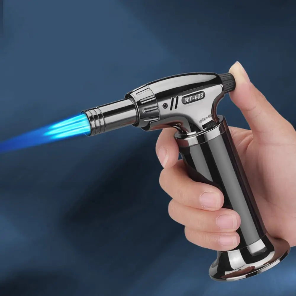 Hand holding a butane torch with blue flame against a dark background