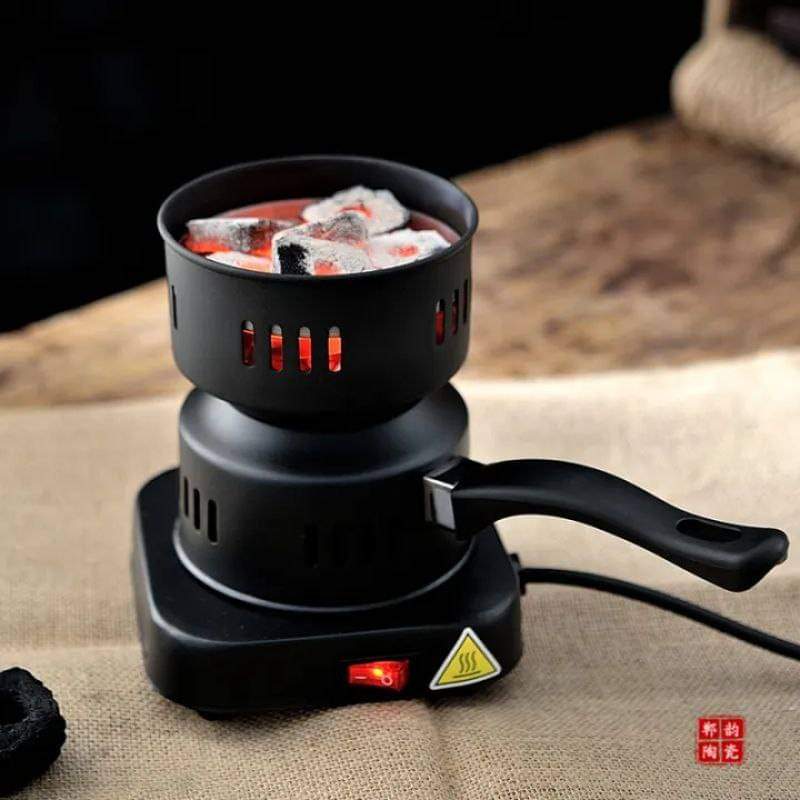 Black electric heater with a pot containing ice and red material on a textured surface.