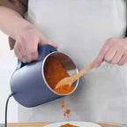 Person using a small electric grinder to pour orange powder onto a plate