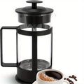 Black French press coffee maker with a cup of coffee and beans on a white background