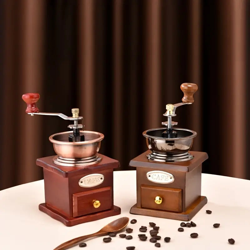 Two vintage-style coffee grinders on a white surface with a brown curtain background.