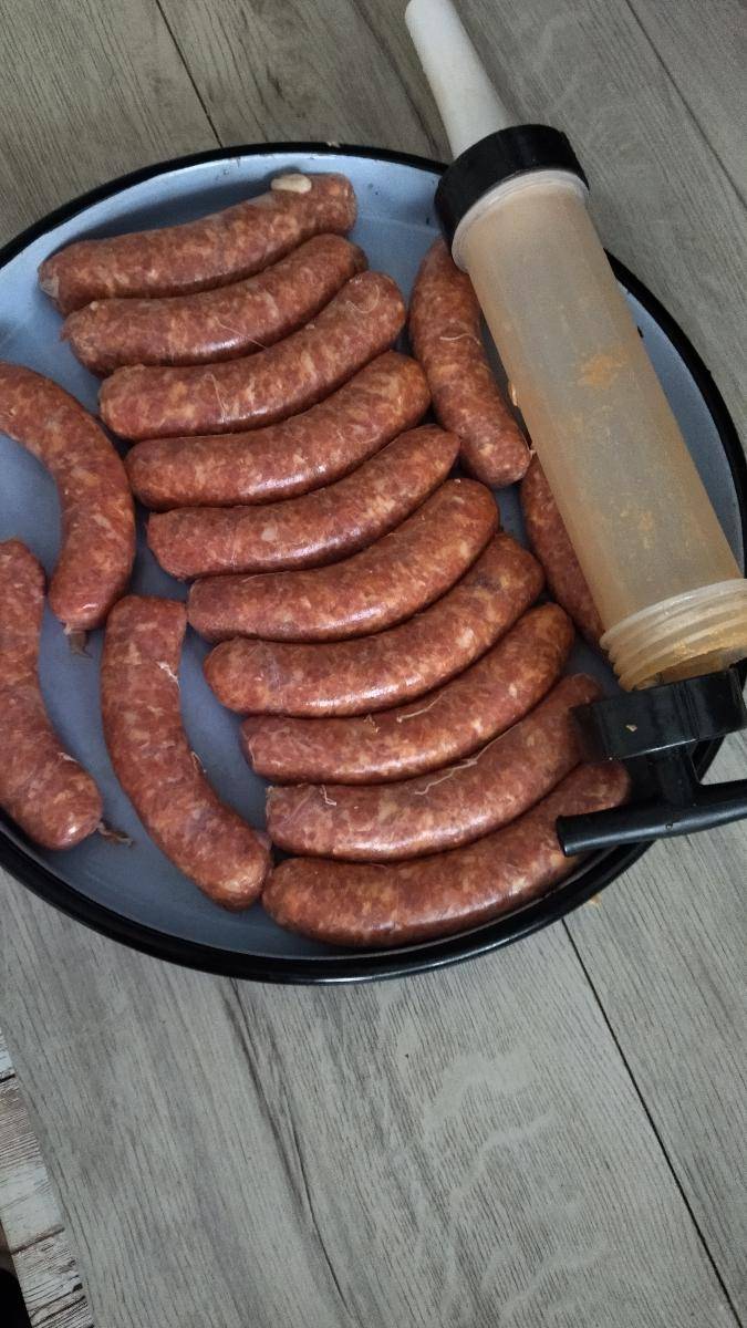 Raw sausages on a plate with a sausage filler on a wooden surface