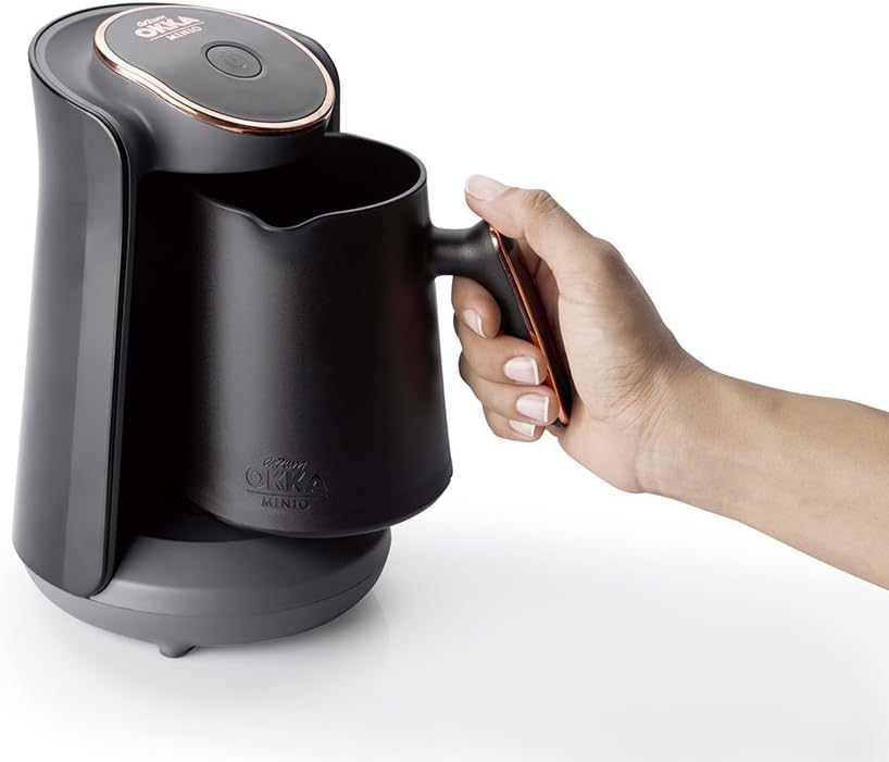 Black electric kettle held by a hand on a white background