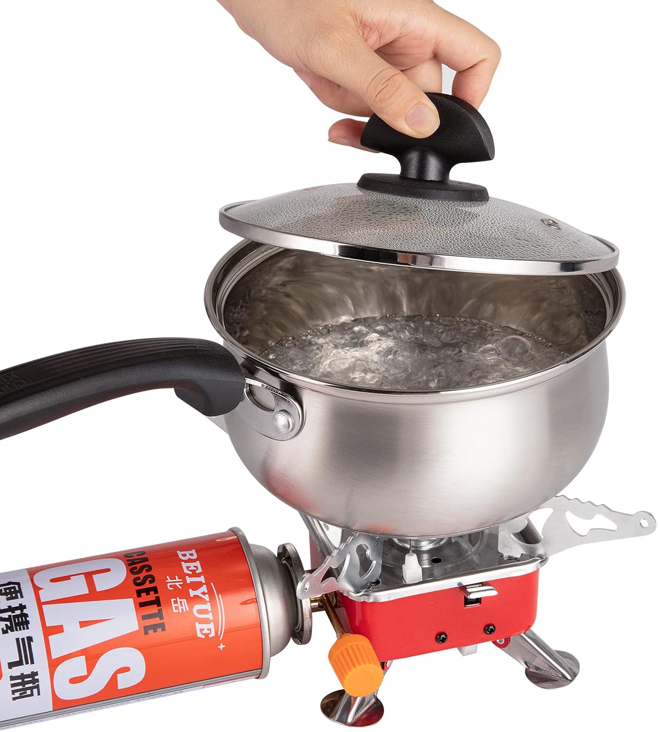 Stainless steel pot with lid on a portable gas stove, with a hand holding the lid.