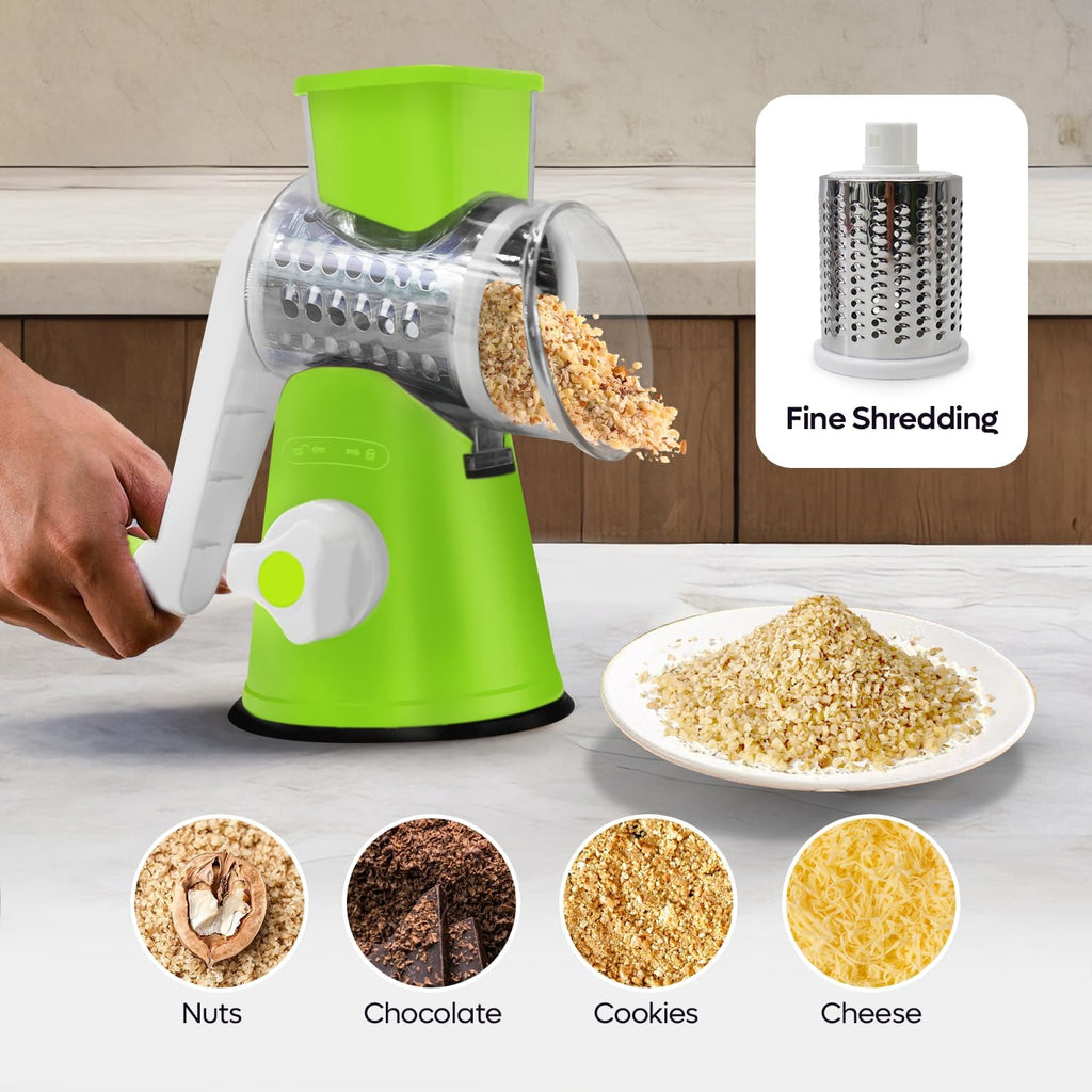 Green manual grater with shredded ingredients on a kitchen counter, showing uses for nuts, chocolate, cookies, and cheese.