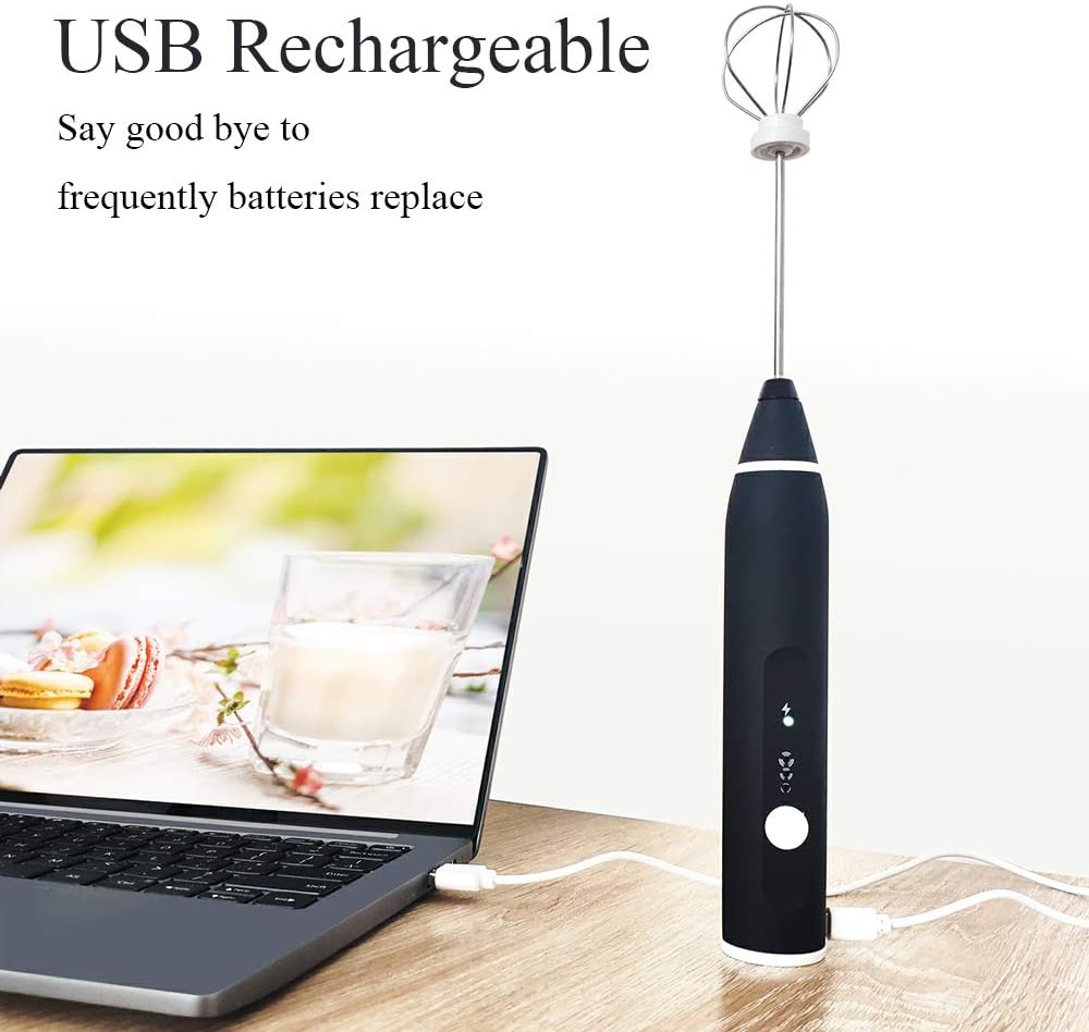 Black USB rechargeable hand mixer on a wooden surface with a laptop displaying a recipe.