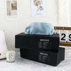 Black boxes with blue towel on a marble surface, candle nearby