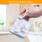 Hand holding a soapy scrubber with a blurred kitchen background