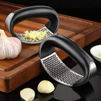 Garlic press on a wooden cutting board with garlic cloves and minced garlic.