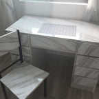 White marble-style desk with a chair in a room with sheer curtains.