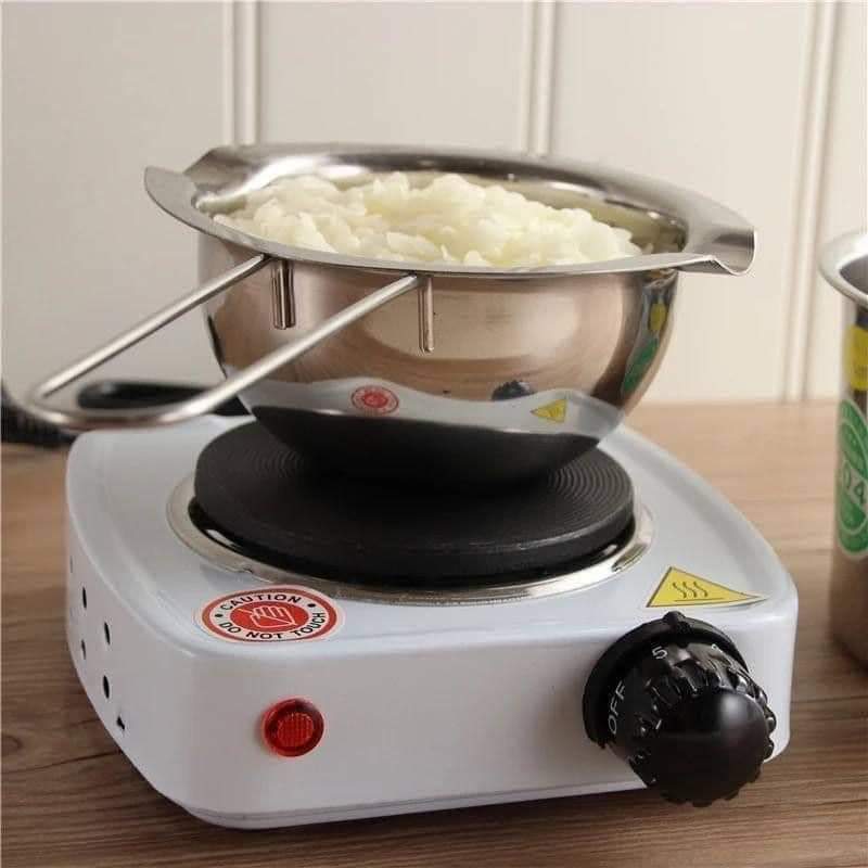 Small electric stove with a metal bowl containing food on a wooden surface.
